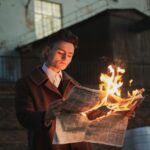 man reading burning newspaper