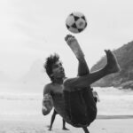 grayscale photography of man playing soccer
