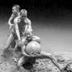 boys wrestling in muddy water with large ball