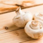 three white mushrooms on beige wooden table
