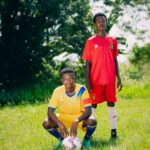 two young soccer players standing on a grass field